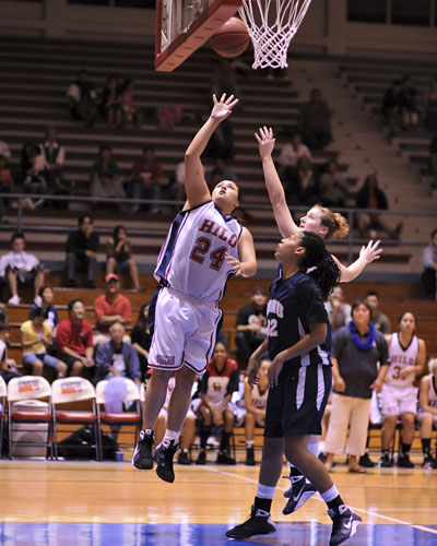 Hilo's Sheila Azevedo lays up the ball beyond the reach of NDNU's #23 Jennifer Dreessen and #32 Tanaia Keyes.
