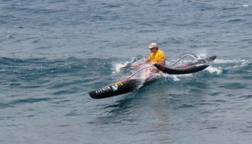 An OC-1 paddler comes in with a flying ama into the finish.