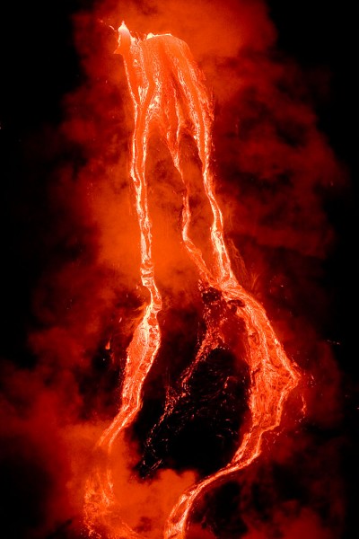 Lava streams down the Waikupanaha bench west of Kalapana. The quick moving pahoehoe lava cascades down into the ocean.