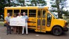 Harold Hughes (left), vice president and area manager at First Hawaiian Bank - Kamuela Branch, and Vicki Hasty, vice president of First Hawaiian Bank Business Banking and Team Leader West Side of the Island of Hawaii, present a check to Hawaii Preparatory Academy's Keawe Liu, assistant headmaster for external relations, and Lindsay Barnes (right), headmaster. The group is pictured in front of one of the school's two new buses purchased with grant funds from the First Hawaiian Bank Foundation.
