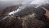 This photo looks northeast and shows Puʻu ʻŌʻō crater. Recent activity has been focused around a few spatter cones on the crater floor. At the far edge of the crater, a small lava pond has been active and has been the source of flows extending northeast of Puʻu ʻŌʻō. Those flows are visible at the top-center of the photo. Just below the horizon two small sources of smoke mark where the flow front is burning lichen and moss covering older ʻaʻā flows. Photo courtesy of USGS/HVO