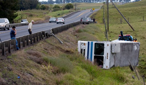 20081211_earls-snack-truck-2 Miles Saito, left, owner of the Earl's Snack Shop truck which overturned alongside Highway 19 just west of Waimea Country Club. Don Winters, center, is the pasture owner where the truck rolled down the embankment. Ted Alip, right, uses a winch on his tow truck to right the vehicle.