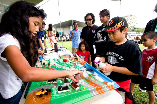 20090425_oceanday-runoff Ericka Paiva, left, sprinkles some dye onto a miniature cityscape as Kinyaaaanii Padilla, right, provides the simulated rainstorm in a demonstration of water runoff at the Department of Health Clean Water Branch booth.