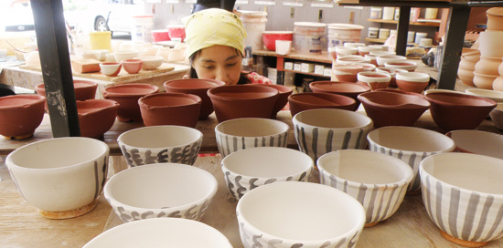 TomokoNakazato Director of DMAC's ceramic department Tomoko Nakazato drowning in a sea of bowls. (Photo courtesy of Donkey Mill Art Center)
