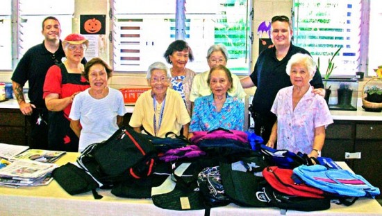backpacks-drive Community Police Officers Scott Amaral, left, and Sandor Finkey pose with volunteers of the Kea'au Nutrition Center, who donated 25 bags to a backpack charity drive.