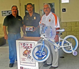 CopsToys4Tots Elsworth Fontes of the Rock & Roll Motorcycle Club, left, poses with Sergeant Regino Saludares and Officer John Stewart (holding bike) at the South Hilo police station, one of eight Police Department donation points for Toys for Tots. (Photo courtesy of the Police Department)