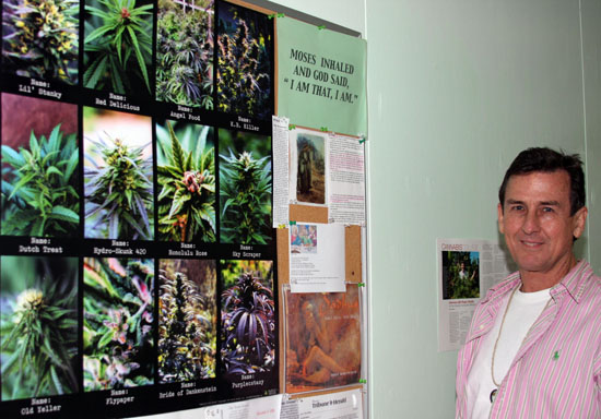 stands next to a bulletin board in his downtown Hilo office. (Hawaii 24/7 photo sourtesy of Tim Wright)