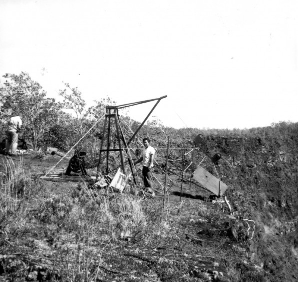 1956_usgs-kilauea-volcano-tram Hawaii Volcanoes National Park. Tramway used to transport equipment from the rim to the crater floor of Kilauea Volcano in 1965-67. Scale is given by the wooden box which is about 1 meter long. A three-eighths-inch steel cable is fastened at the upper end to an A-frame set in concrete and at the lower end to a chain wrapped around the island. Equipment is lowered in a wooden box attached to a pulley running on the steel cable. A rope attached to the box is reeled on a winch (to the left of the A-frame) which in turn is connected by rope to a pulley attached to the axle of a jeep, jacked up, and blocked in position (not shown). Circa 1965. USGS Photo