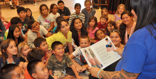 Hakunani Anakalea, group leader at the A+ program at Holualoa Elementary School, reads “Pearl Harbor Warriors: The Bugler, The Pilot, The Friendship.” (Photo courtesy of Fern Gavelek Communications)