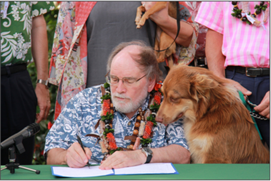 Gov. Neil Abercrombie signs several animal protection bills as Sen. Clayton Hee's dog, Kahekili, and others look on. (Photo courtesy of the Office of the Governor)