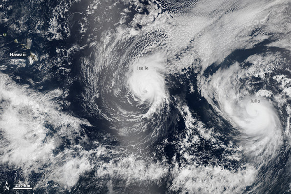 On August 5 2014, the Visible Infrared Imaging Radiometer Suite (VIIRS) sensor on Suomi-NPP captured natural-color images of both Iselle and Hurricane Julio en route to Hawaii. The image above is a composite of three satellite passes over the tropical Pacific Ocean in the early afternoon. Note that Iselle’s eyewall had grown less distinct; the storm had descreased to category 2 intensity. The bright shading toward the center-left of the image is sunglint, the reflection of sunlight off the water and directly back at the satellite sensor. NASA image by Jeff Schmaltz, LANCE/EOSDIS Rapid Response.