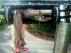 A photo of a 1,200-pair cable and a splicing tool inside of a splice case. The case is placed over the cut or damaged section and the cables are pulled through it. Hawaiian Telcom technicians must open each colored sheath to expose the copper wire and then splice or connect each wire in the proper sequence at each end of the wire using the splicing tool. This equates to 2,400 individual splices, which can be done by one or two splicers at a time. It is precise, labor-intense work that takes time. Photo courtesy of HawaiianTel.