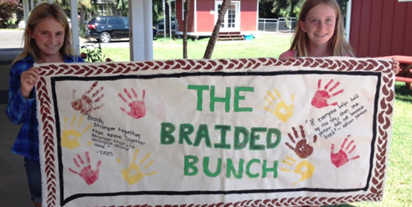 Parker 6th graders hold a sign they made about the significance of the braid, after their recent visit to Pukalani Stables. (Photo courtesy of Parker School)