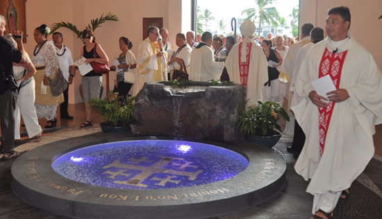 Father Konelio “Lio” Faletoi (right) walks around the new baptismal font. (Photo courtesy of St. Michael the Archangel Church)