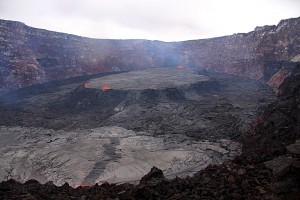 This textbook example of a perched lava lake that formed within the Pu‘u ‘Ō‘ō crater in May 2011 shows what could happen with Kīlauea’s current summit lava lake if overflows of the Overlook crater vent continue. Lava overflowing the vent rim could build a levee around the lake, increasing the height of the vent rim and resulting in a perched lava lake within Halema‘uma‘u Crater. USGS photo.