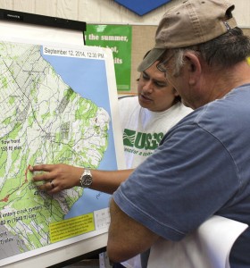 In September 2014, during one of many community meetings held in Pāhoa to address concerns about Kīlauea Volcano’s June 27th lava flow, USGS Hawaiian Volcano Observatory scientist Kevan Kamibayashi points out the flow’s advance as of that week. These one-on-one interactions with Puna residents were an effective means of answering specific questions and providing factual, up-to-date information about the lava flow. USGS photo.
