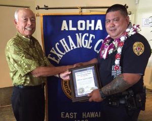 Aloha Exchange Club member Joey Estrella presents an 'Officer of the Month' award to Officer Jared Cabatu.