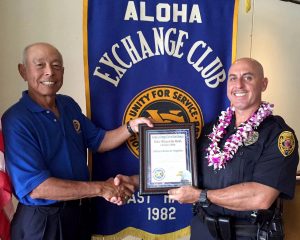 Aloha Exchange board member Joey Estrella presents an 'Officer of the Month' award to Officer Roberto Segobia.