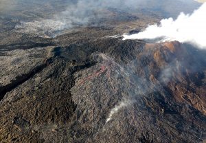 On May 24, 2016, two new flows broke out on the flanks of the Puʻu ʻŌʻō cone on Kīlauea Volcano's East Rift Zone. The silvery sheen of new lava erupting from the northern 61f breakout (center) and eastern 61g breakout (upper left) stands out in contrast to the older flows on and around Puʻu ʻŌʻō (right). The 61f flow stagnated within two weeks, but the 61g flow, which advanced downslope and reached the ocean on July 26, 2016, remains active today. USGS photo.