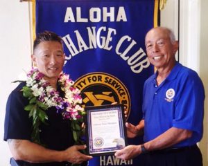 Aloha Exchange board member Joey Estrella presents an 'Officer of the Month' award to Officer Paul Mangus.