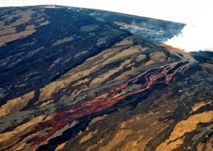 Aerial view of Mauna Loa erupting on the morning of March 25, 1984, the first day of the volcano’s most recent eruption. The lava flow was advancing southeast, toward Kīlauea, from fissure vents at an elevation of about 11,200 feet on Mauna Loa’s Northeast Rift Zone. Moku‘āweoweo, Mauna Loa’s summit caldera, is visible at top left. USGS photo by J.P. Lockwood.