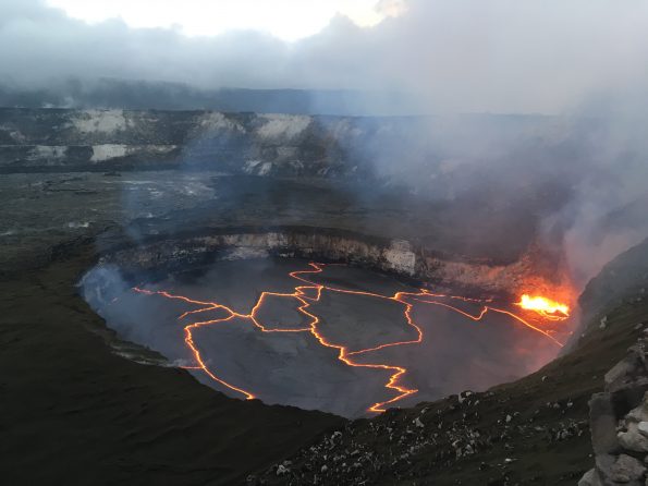 Early evening view of the lava lake within Halemaʻumaʻu crater at the summit of Kīlauea Volcano on January 30, 2018, when the lake level was 27 m (88 ft) below the crater floor. The bright yellow area of spattering marks the location where the circulating lava descends into the lake, thereby releasing gases trapped beneath the solid black crust on the lake surface. The area around Halemaʻumaʻu remains closed due to ongoing volcanic hazards associated with the lava lake, including high levels of sulfur dioxide gas and unexpected rockfalls and explosions. USGS photo by M. Patrick.