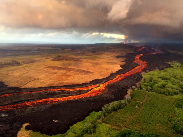 The fissure 8 vent (far distance, upper right) continues to feed an active lava channel on Kīlauea Volcano’s lower East Rift Zone, shown here on July 26, 2018. Based on several monitoring techniques, the USGS recently estimated that lava is erupting from fissure 8 at a rate of 50 to 150 cubic meters per second (65–196 cubic yards per second), or roughly, 1.1 to 3.4 billion gallons per day. USGS photo by L. DeSmither.