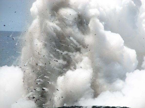 This telephoto image shows dark fragments of molten and semi-solid lava being blasted upward and outward during a hydrovolcanic explosion at the Waikupanaha ocean entry west of Kalapana in April 2008. Similar explosions are occurring at Kīlauea Volcano's current lower East Rift Zone ocean entry. For more information, please see "Littoral hydrovolcanic explosions: a case study of lava–seawater interaction at Kilauea Volcano" (https://volcanoes.usgs.gov/vsc/file_mngr/file-186/Mattox and Mangan_hydrovolcanic explosions.pdf). USGS photo by M. Patrick.