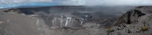 In this panoramic view, Hawaiʻi Volcanoes National Park’s Crater Rim Drive (left foreground) disappears into the enormous void created by the collapse of Halema‘uma‘u and portions of the Kīlauea caldera floor during the dramatic events at the summit of the volcano in May-August 2018. USGS photo by D. Dzurisin.