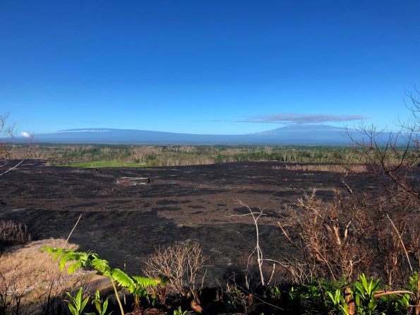 Low sulfur dioxide gas emissions on Kīlauea have resulted in greatly diminished vog (volcanic air pollution) in Hawaii, giving rise to spectacular views on the island. Here, looking across the field of lava erupted from Kīlauea's lower East Rift Zone this past summer, the shield-shaped profiles of Mauna Loa (left) and Mauna Kea (right) can be clearly seen in the far distance. Photo taken Wednesday, October 10, 2018 courtesy of U.S. Geological Survey