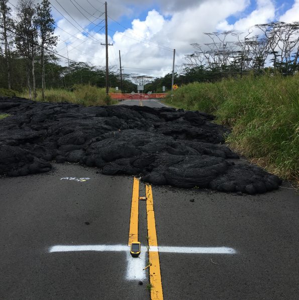 A high-precision GPS unit (on white “T” in foreground) records its position at a ground control point along Pohoiki Road. This marker was painted in July 2018 and is visible in numerous aerial photographs taken by Hawaiian Volcano Observatory geologists throughout Kīlauea’s lower East Rift Zone eruption last summer. GPS data are recorded over a period of four minutes at each location, enabling vertical precision of approximately 18 cm (7 in). USGS photo by M. Zoeller, 03/22/2019.